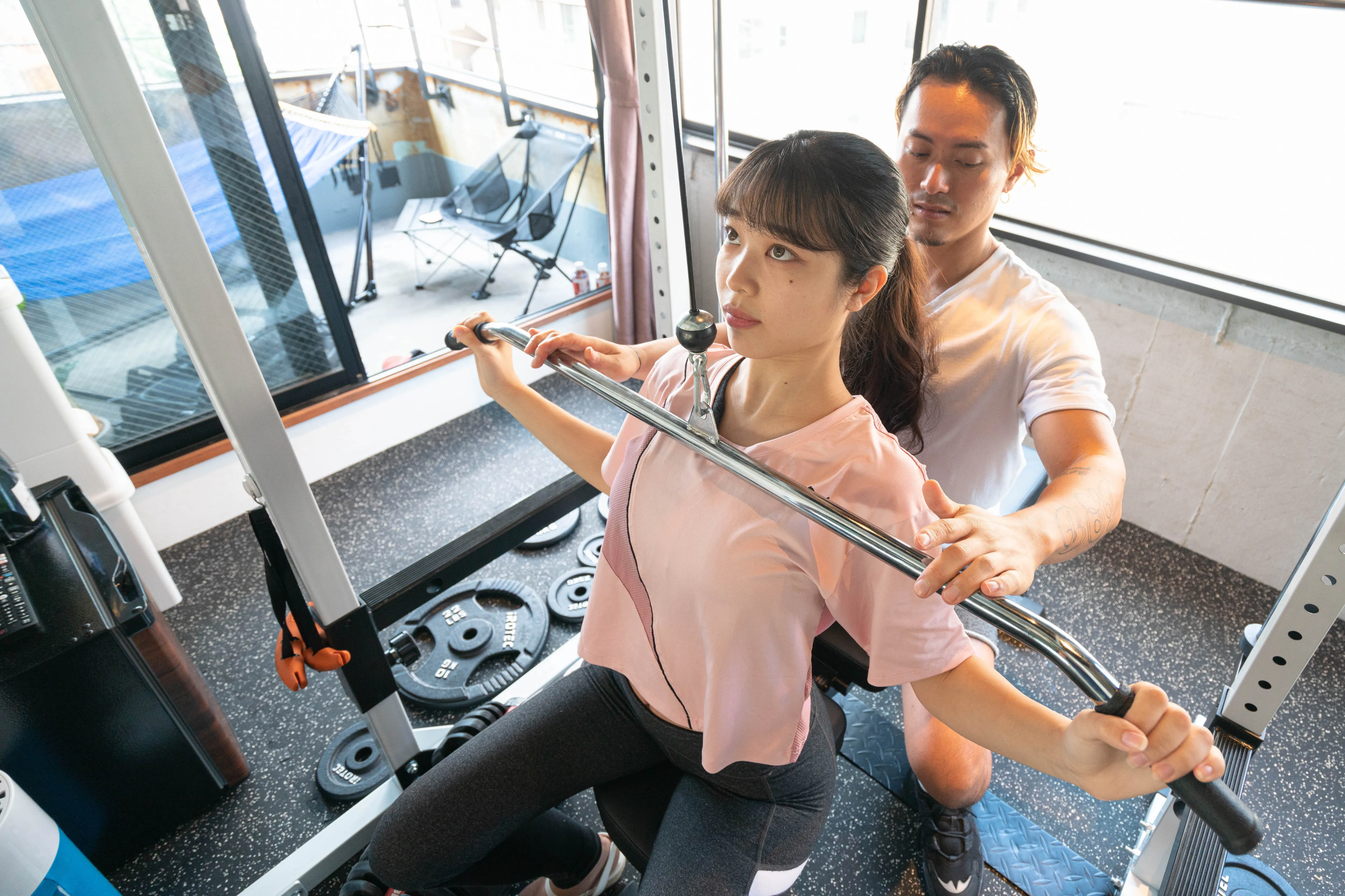 トレーナーがパーソナルジムの利用者にマシントレーニングを指導している様子